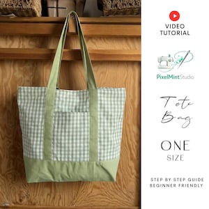 May include: A green and white gingham tote bag with a solid green base and straps. The bag has a front pocket and is hanging against a wooden background. Text on the image reads "Tote Bag" and "One Size".