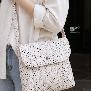Puede incluir: Bolso bandolera color crema con cierre de solapa, cubierto de pequeños lunares negros. El bolso tiene un diseño acolchado y una correa larga. El texto "STEP BY STEP GUIDE BEGINNER FRIENDLY" está en la parte inferior de la imagen.