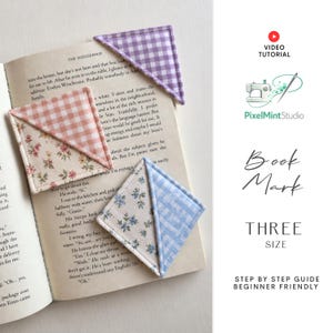 Puede incluir: Tres marcapáginas de esquina de tela triangulares sobre un libro abierto. Uno es de cuadros morados, otro de cuadros color melocotón con estampado floral y otro de cuadros azules con estampado floral azul. Texto: Video Tutorial, PixelMintStudio, Book Mark, Three Size.