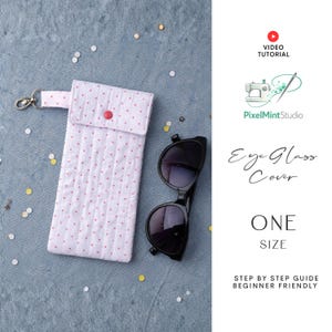 Può includere: Un astuccio per occhiali bianco a pois rossi con chiusura a scatto e chiusura argentata, accanto a un paio di occhiali da sole neri. L'astuccio è trapuntato e presenta il testo "Eye Glass Cover" e "ONE SIZE".