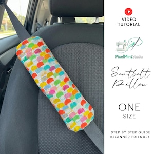 Puede incluir: Una almohada colorida para cintur&oacute;n de seguridad con un patr&oacute;n de formas multicolores. La almohada est&aacute; envuelta alrededor de un cintur&oacute;n de seguridad negro en un coche. El texto "Seatbelt Pillow" y "One Size" son visibles.