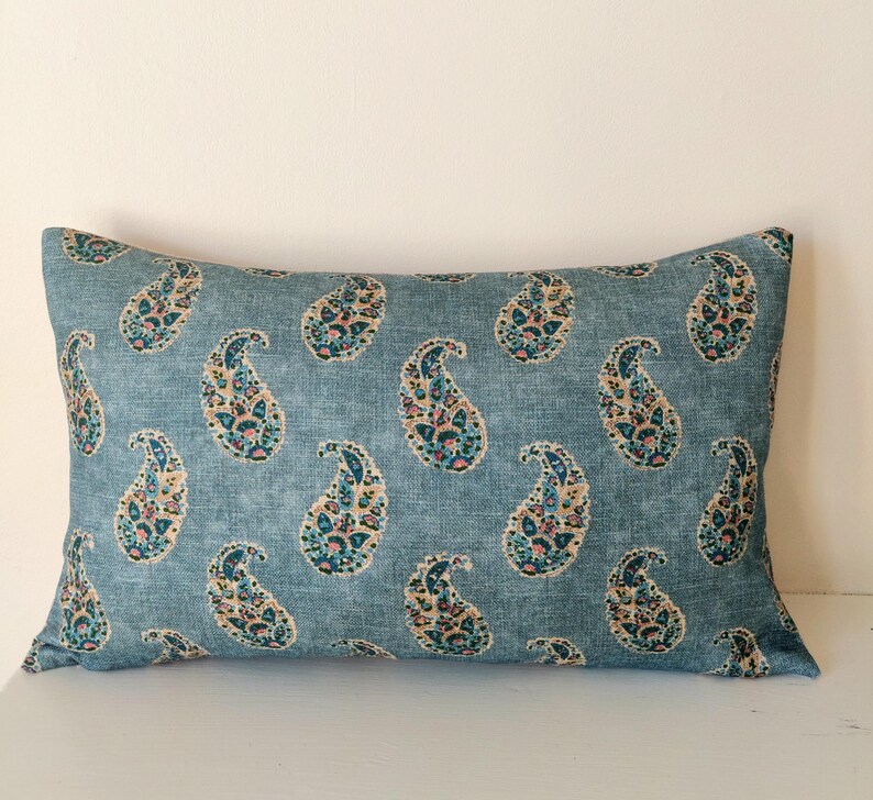 May include: A blue throw pillow with a paisley pattern in shades of pink, teal, and brown.