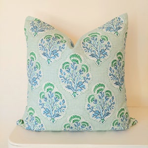 May include: A light green throw pillow with a blue and green floral pattern. The pillow is made of a soft, comfortable fabric and has a subtle sheen.