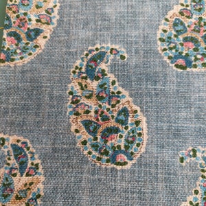 May include: Blue paisley fabric with a white background. The paisley pattern is in shades of blue, green, and pink.