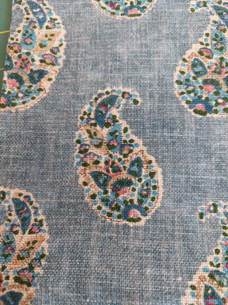 May include: Blue paisley fabric with a white background. The paisley pattern is in shades of blue, green, and pink.