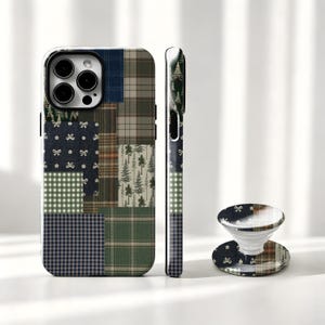 May include: A smartphone case and a matching circular collapsible phone grip featuring a patchwork design. The pattern includes navy blue with white bows, green and white gingham, dark green plaid, and a forest print with evergreen trees.