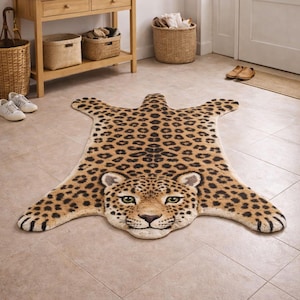 May include: A leopard-print rug with a detailed face and spotted pattern. The rug is tan with black spots and green eyes, designed to resemble a leopard skin. The rug is placed on a tiled floor.