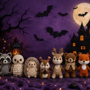 Puede incluir: Una colección de siete animales de peluche tejidos a ganchillo, incluyendo un mapache, un búho, un erizo, una ardilla, un ciervo, un oso y un zorro alineados. Cada figura presenta puntadas detalladas y rasgos faciales bordados.