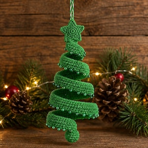 Puede incluir: Un adorno navideño en forma de espiral hecho de ganchillo verde, con una pequeña estrella en la parte superior y una serie de diminutas cuentas verdes fijadas a lo largo de los bordes de la estructura de hilo, colgado de un cordel trenzado.