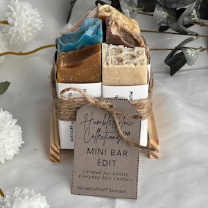Könnte beinhalten: Eine Sammlung von Mini-Seifen in verschiedenen Farben, darunter Blau, Braun und Beige, die mit Bindfaden zusammengebunden sind. Ein Etikett lautet "Humbler Flow Collections MINI BAR EDIT Curated for Gentle, Everyday Skin Comfort NurseCrafted Skincare."