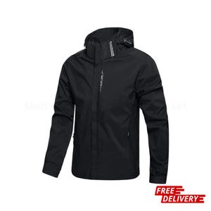 Op de afbeelding: Zwarte jas met capuchon, ritssluiting en meerdere zakken. Het woord "EXPLORE" staat verticaal op de borst gedrukt. De jas is ontworpen voor buitenactiviteiten en is waterdicht.