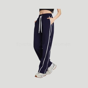May include: Navy blue athletic pants with white side stripes and a drawstring waist. The pants have pockets and are worn with white and gray athletic shoes. The text "Sports Women" is visible on the left side of the image.