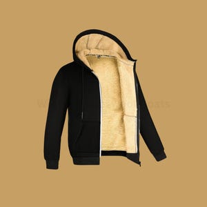 May include: A black hooded jacket with a zip-up front and a tan, fluffy lining. The jacket has a drawstring and two front pockets. The zipper is white. The jacket is made of a soft material.