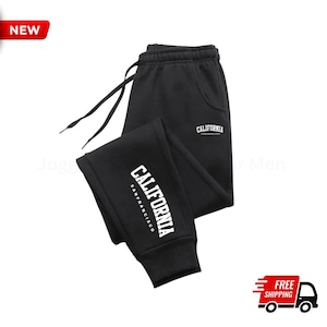 Könnte beinhalten: Schwarze Jogginghose mit weißem Text "CALIFORNIA SAN FRANCISCO" am linken Bein. Das Wort "CALIFORNIA" ist auch auf dem rechten Bein aufgedruckt. Die Jogginghose hat einen Kordelzug und Taschen. Ein rotes "NEW"-Tag befindet sich in der oberen linken Ecke.