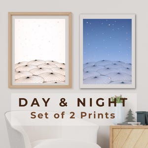 以下が含まれることがあります： 「DAY & NIGHT」と書かれた2つの額入りプリント。片方は点々のある明るい背景、もう片方は星空の青い空。どちらも様式化されたパラソルが描かれています。下には「DAY & NIGHT Set of 2 Prints」の文字。