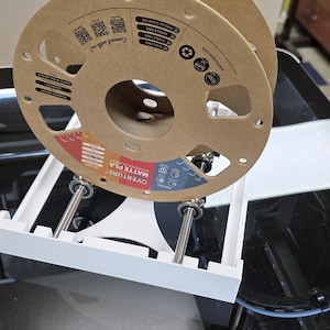 May include: A brown cardboard spool of Overture Matte PLA filament is mounted on a white 3D printer. The spool has printed text and graphics, including "Connect with us!" and "Precise Diameter."