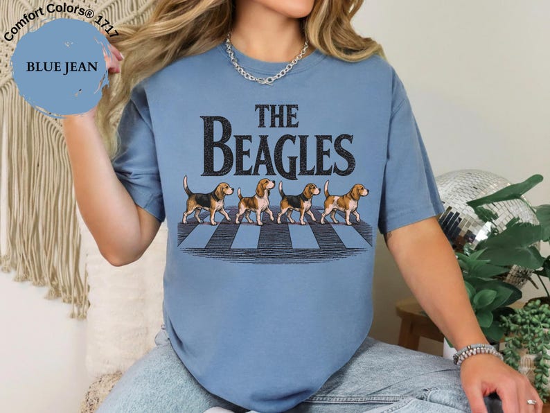 May include: Blue jean coloured t-shirt with the text "THE BEAGLES" in black, featuring an illustration of four beagles crossing a crosswalk. The shirt is a Comfort Colors 1717 style.