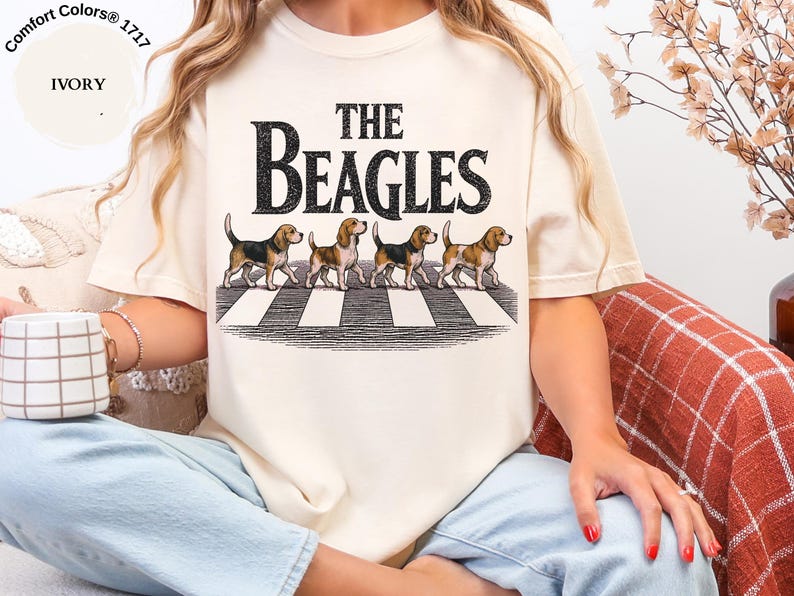 May include: Ivory t-shirt with the words "THE BEAGLES" and an illustration of four beagles on a zebra crossing. The shirt is a Comfort Colors 1717 style.