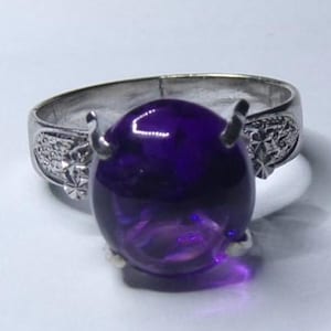 Puede incluir: Un anillo de plata con una gran amatista ovalada. El anillo tiene un dise&ntilde;o floral en la banda.