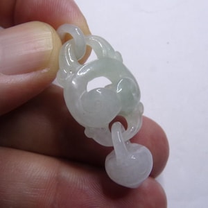 Peut inclure: Un pendentif en jade blanc avec un motif sculpt&eacute; de n&oelig;ud. Le pendentif est attach&eacute; &agrave; une perle ronde en jade.