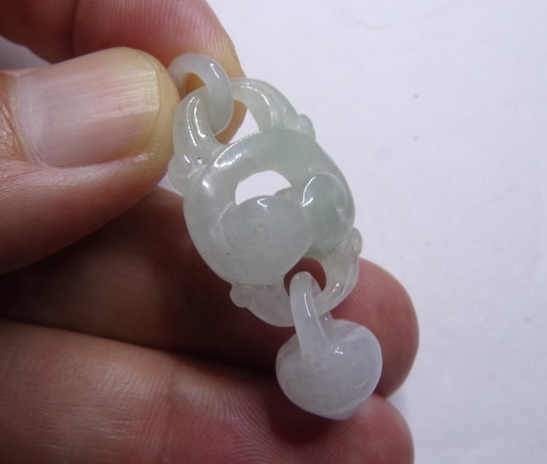 Peut inclure: Un pendentif en jade blanc avec un motif sculpt&eacute; de n&oelig;ud. Le pendentif est attach&eacute; &agrave; une perle ronde en jade.