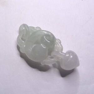 Peut inclure: Un pendentif en jade blanc sculpt&eacute; en forme de n&oelig;ud stylis&eacute; avec un d&eacute;tail en forme de c&oelig;ur. Le pendentif est lisse et poli.