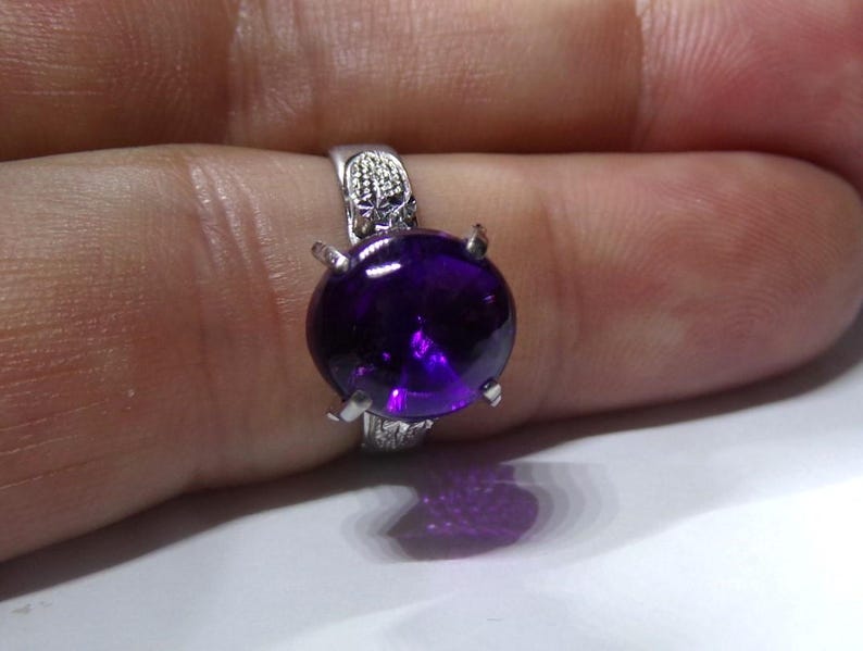 Puede incluir: Un anillo de plata con una gran amatista redonda y p&uacute;rpura engastada en garras.