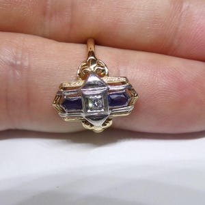 May include: A gold ring with a geometric design featuring a central diamond and two blue sapphires.