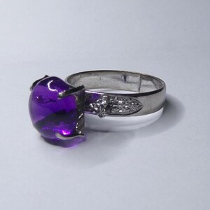 Puede incluir: Un anillo de plata con una piedra preciosa redonda grande de color p&uacute;rpura.