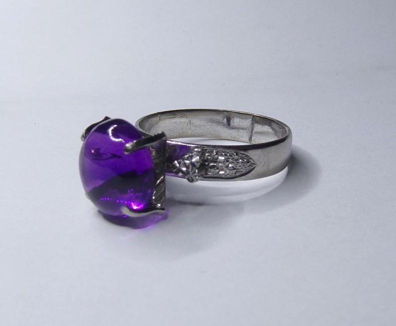 Puede incluir: Un anillo de plata con una piedra preciosa redonda grande de color p&uacute;rpura.