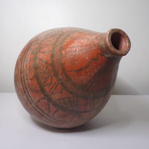 May include: A red clay pot with a round body and a narrow neck. The pot is decorated with black geometric patterns.