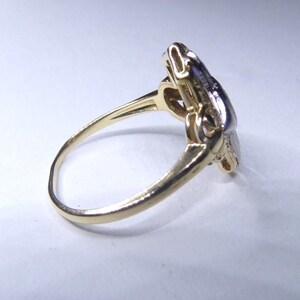May include: A gold ring with a diamond-shaped design set with small diamonds. The ring is made of two-toned gold, with a yellow gold band and a white gold setting.