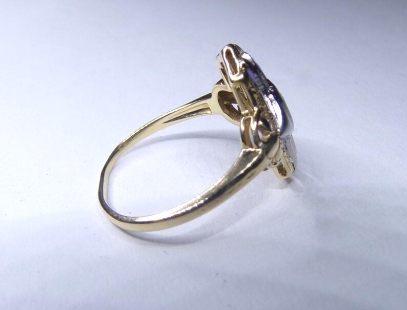 May include: A gold ring with a diamond-shaped design set with small diamonds. The ring is made of two-toned gold, with a yellow gold band and a white gold setting.