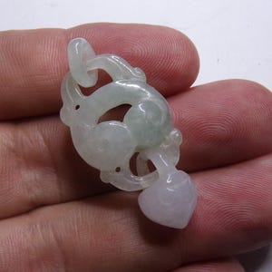 Peut inclure: Un pendentif en jade vert p&acirc;le sculpt&eacute; en forme de dragon stylis&eacute; avec un pendentif en forme de c&oelig;ur en bas.