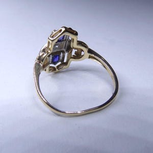 May include: A gold ring with a blue and white stone setting. The ring is set in a delicate, intricate design.