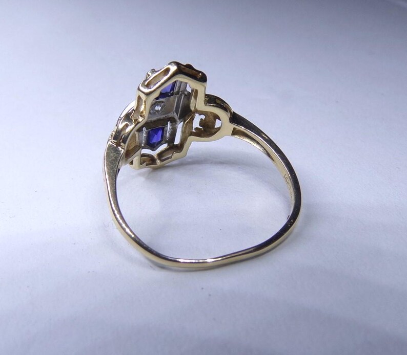 May include: A gold ring with a blue and white stone setting. The ring is set in a delicate, intricate design.