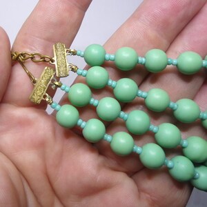 May include: A multi-strand necklace with green beads and gold clasps.