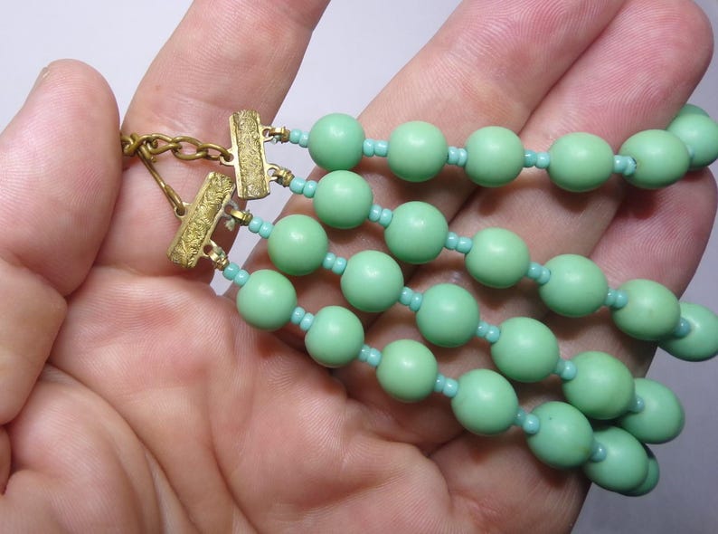May include: A multi-strand necklace with green beads and gold clasps.