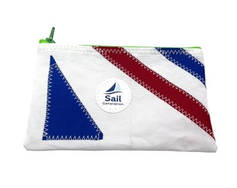 Può includere: Una pochette rettangolare bianca con cerniera, caratterizzata da una toppa triangolare blu, una striscia diagonale rossa e una striscia diagonale blu. Una toppa circolare bianca centrale mostra l'icona di una barca a vela e il testo Sail Generation.