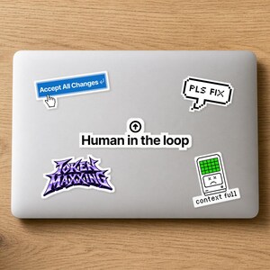 May include: A silver laptop lid decorated with five stickers: a blue button reading Accept All Changes, a pixelated speech bubble saying PLS FIX, a central Human in the loop label, a purple Token Maxxing logo, and a green context full icon.