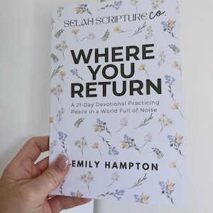 May include: A softcover book titled Where You Return: A 21-Day Devotional Practicing Peace in a World Full of Noise by Emily Hampton, published by Selah Scripture Co. The white cover features a delicate pattern of small blue and yellow flowers.