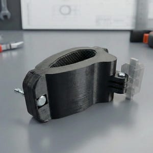 Peut inclure: Un accessoire de vélo noir avec un intérieur texturé et une fixation en plastique transparent. L'accessoire est fixé avec une vis argentée et est conçu pour maintenir un appareil. Des outils sont visibles en arrière-plan.