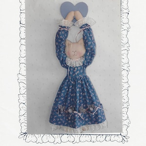 Puede incluir: Una muñeca de gato de tela con un vestido azul de flores, cuello y puños de encaje blanco, sosteniendo un corazón morado. El vestido presenta cuatro pequeñas figuras de ratón gris en el dobladillo. El texto dice SEW SPECIAL y Play Cat and Mouse 29 inches long.