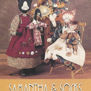 May include: A sewing pattern cover titled SAMANTHA & SOCKS #IJ232 for 46 cm boy and girl kitty dolls by Indygo Junction Designs. The image displays four fabric cat dolls dressed in various outfits, including dresses, overalls, and shirts.