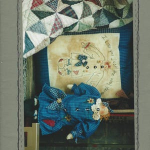 May include: A handmade doll with a blue plaid dress and a white lace collar, lying on a blue patterned surface. The image includes a stitched design with the text "I Like you just the way you are" and "You Are Special". The doll is 13 inches in length.