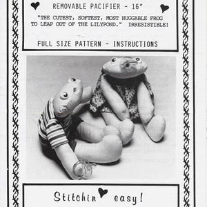 以下が含まれることがあります： 「#01-Froggie Baby」と題された白黒の裁縫型紙シート。ストライプのシャツを着たカエルのぬいぐるみとおしゃぶりをしたカエルのぬいぐるみが写っている。テキストには「REMOVABLE PACIFIER - 40.64 cm」「FULL SIZE PATTERN - INSTRUCTIONS」「Stitchin easy!」などが記載されている。