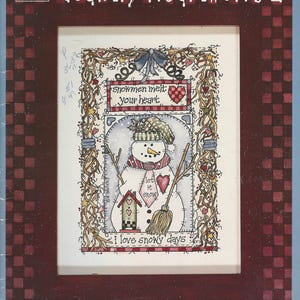 May include: A framed artwork titled "Country Heartworks 2" with a snowman illustration. The snowman has a hat and scarf, holding a broom. Text includes "Snowmen melt your heart" and "I love snowy days." The frame is dark red with a checkered pattern.