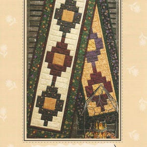 Może przedstawiać: Okładka wzoru zatytułowana Flower Patch Runner Quilt as you go GE-125 od G.E. Designs Iceland. Obraz przedstawia pikowany bieżnik na stół z geometrycznymi blokami z żółtej, bordowej i zielonej tkaniny w kwiaty na jasnobeżowym tle.
