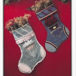 May include: Two decorative Christmas stockings crafted from blue denim fabric. The left stocking features light pink fringe, white lace trim, and a small pocket. The right stocking displays a red and black plaid cuff, pocket, and toe accents.