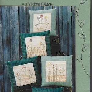 May include: Embroidered cushions with floral designs. Each cushion has a green plaid border and a central square featuring stitched flowers, fences, and suns. The text "PULLING THREADS by joan" is at the top of the image.